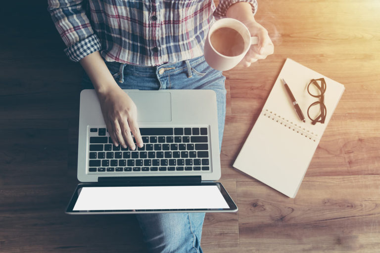 A top down view of a person typing on a laptop with coffee in hand. This could symbolize the comfort of online therapy for moms in Pennsylvania offers. An online therapist in Hershey, PA can tell you more about online postpartum therapy in Pennsylvania and more. 17033