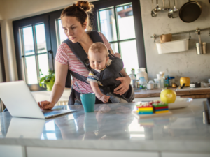 a new mother working at home with her child in a chest carrier
