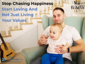 young father with a baby sits in a light green arm chair with a guitar resting against a staircase