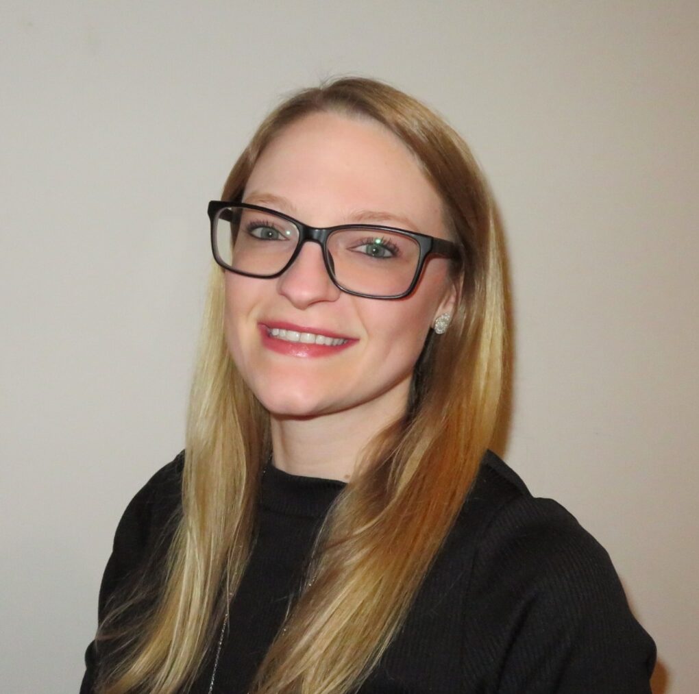 mental health therapist stephanie rineer with long blond health and dark glasses and a black shirt smiles for a professional headshot