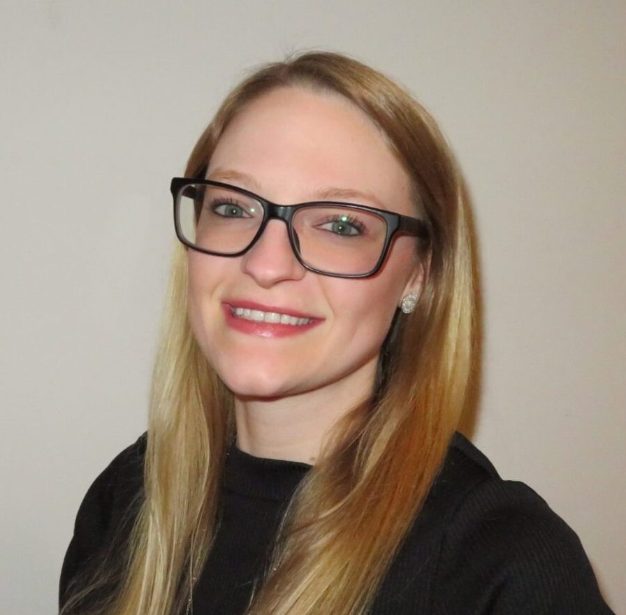 mental health therapist stephanie rineer with long blond health and dark glasses and a black shirt smiles for a professional headshot